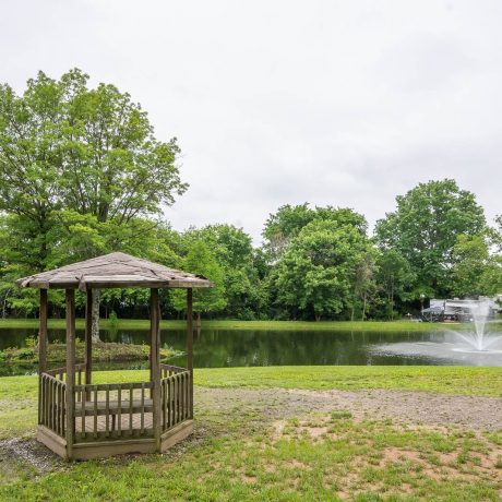 wooden gazebo with lake and fountain behind